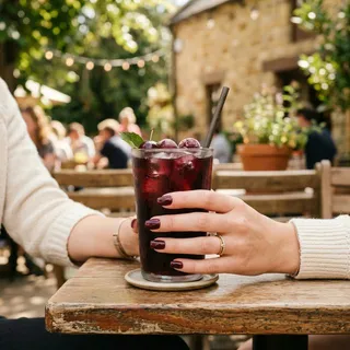 Lifestyle photography of Black Cherry nail color at a cozy outdoor cafe