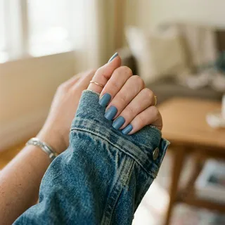 Squoval nails in dusty denim blue resting on vintage denim jacket sleeve