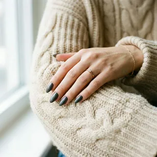 Hand with graphite dark grey nails wearing a cozy winter sweater