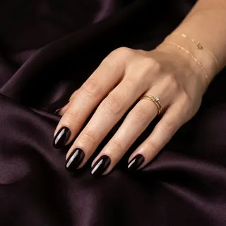 Professional studio product photography of Ink Plum nail color on a dark silk backdrop